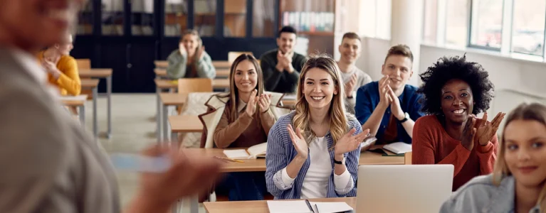smiling, clapping students sitting in a college classroom